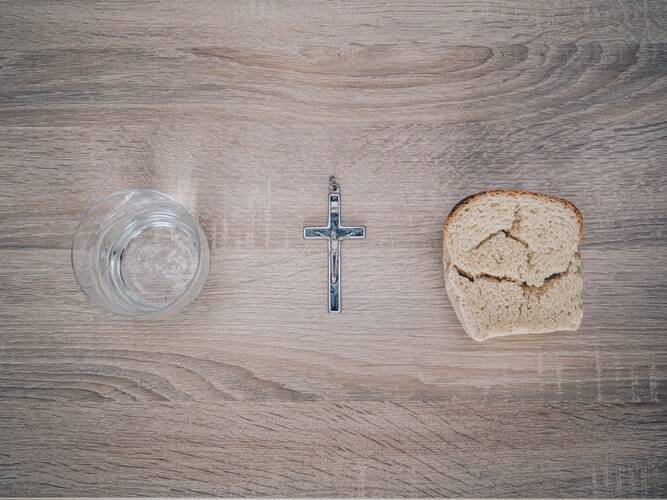 A picture of a glass, a cross, and a piece of bread on the topic of fasting..